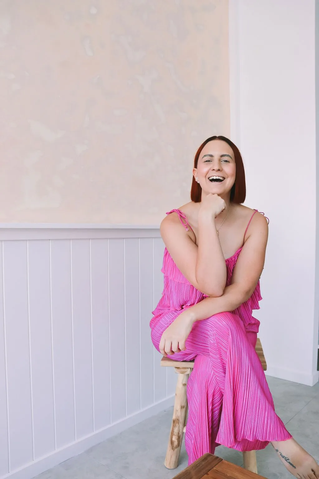 Katie in a pink outfit sitting confidently on a wooden stool